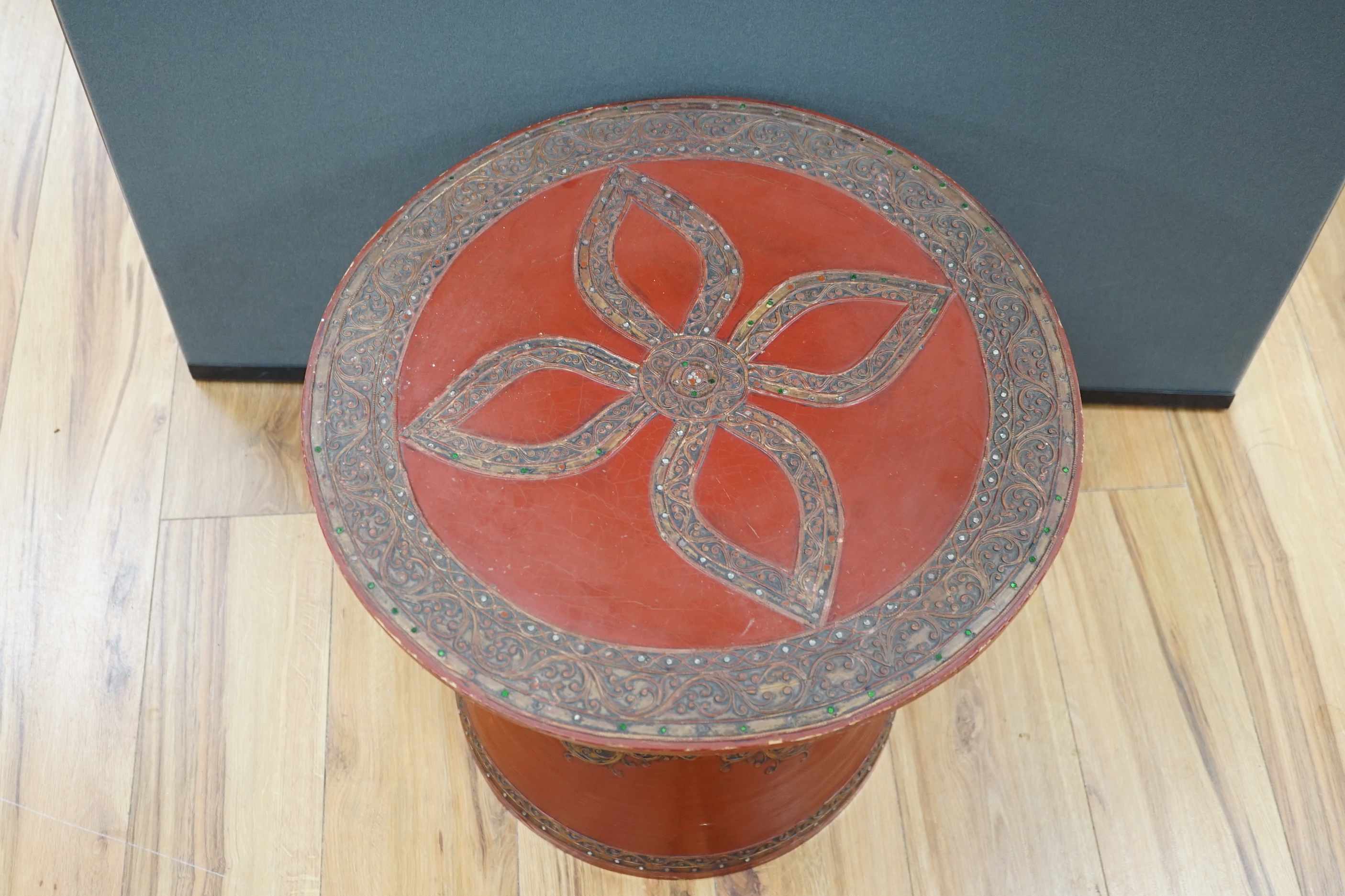 A South East Asian composition red lacquered table inset mirrored sequins, 44cm high x 51cm in diameter